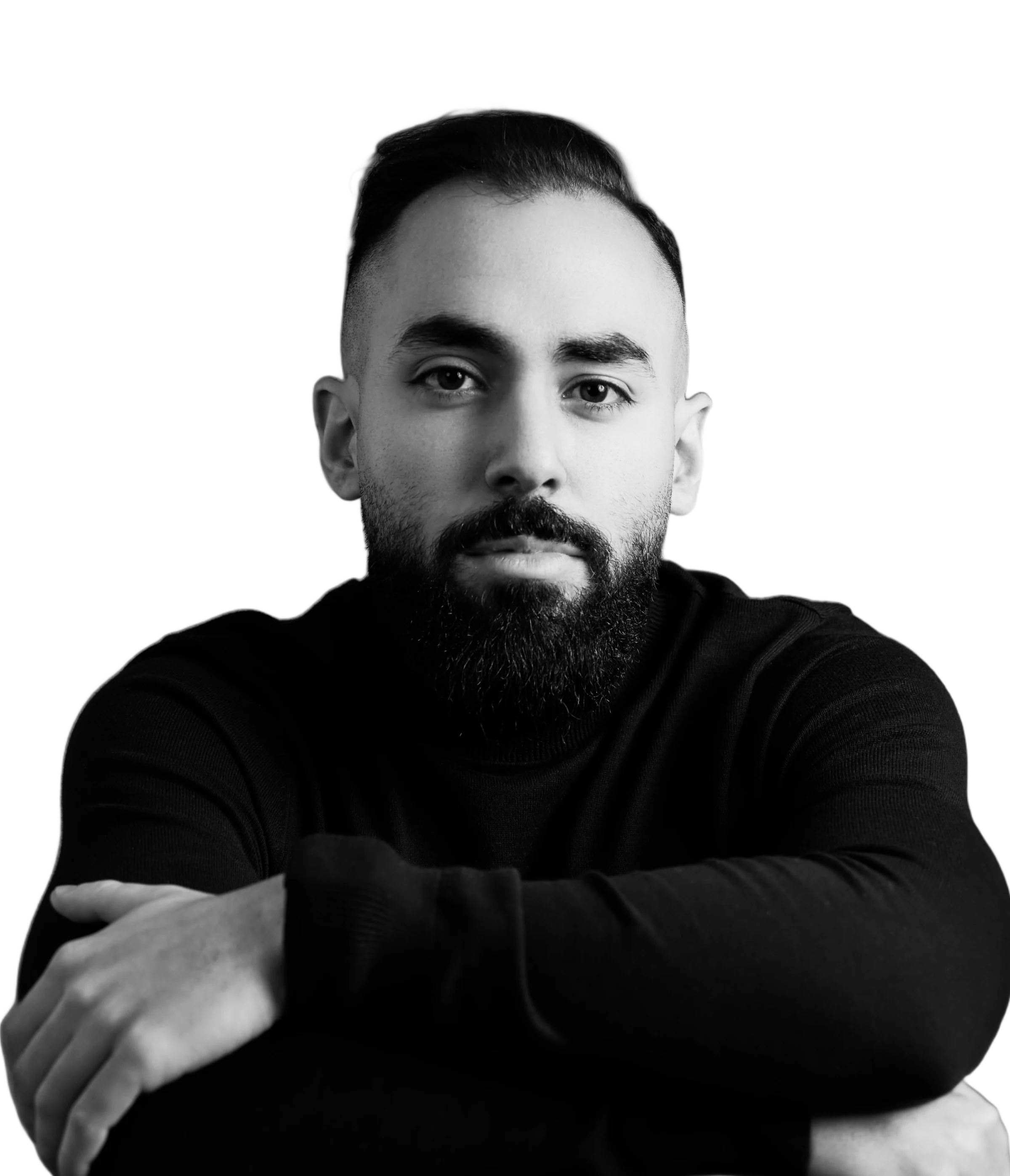Jad Al Masri in a black turtleneck, arms folded over the back of a chair, photographed in black and white