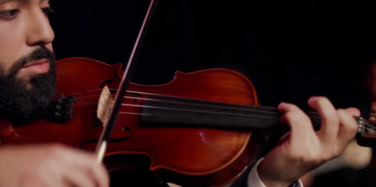 Close-up of Jad playing violin in the dark, from The Disaster X short film