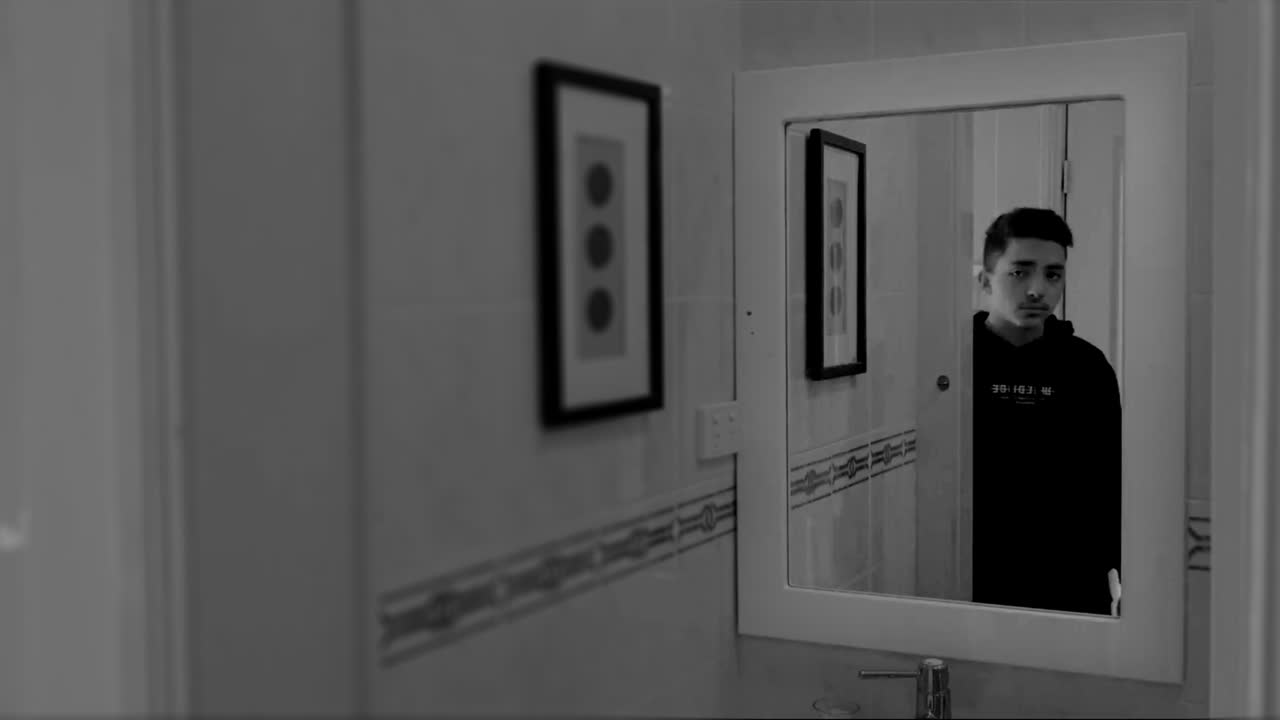 A man reflected in a bathroom mirror, in black and white, from the short film Reflections