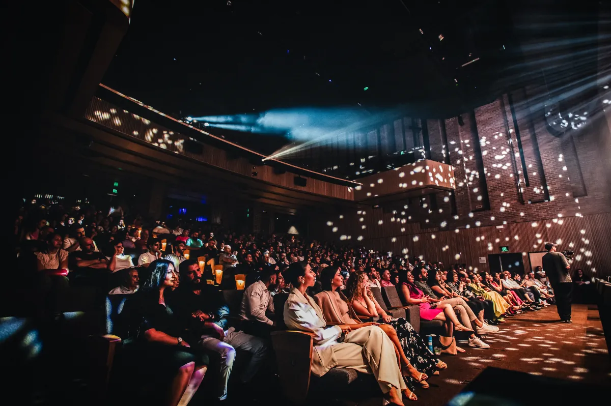 A full house of 430 seen from the stage, under warm stage lights